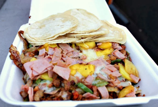 Loaded grilled meat dish with peppers, ham, cheese, and tortillas