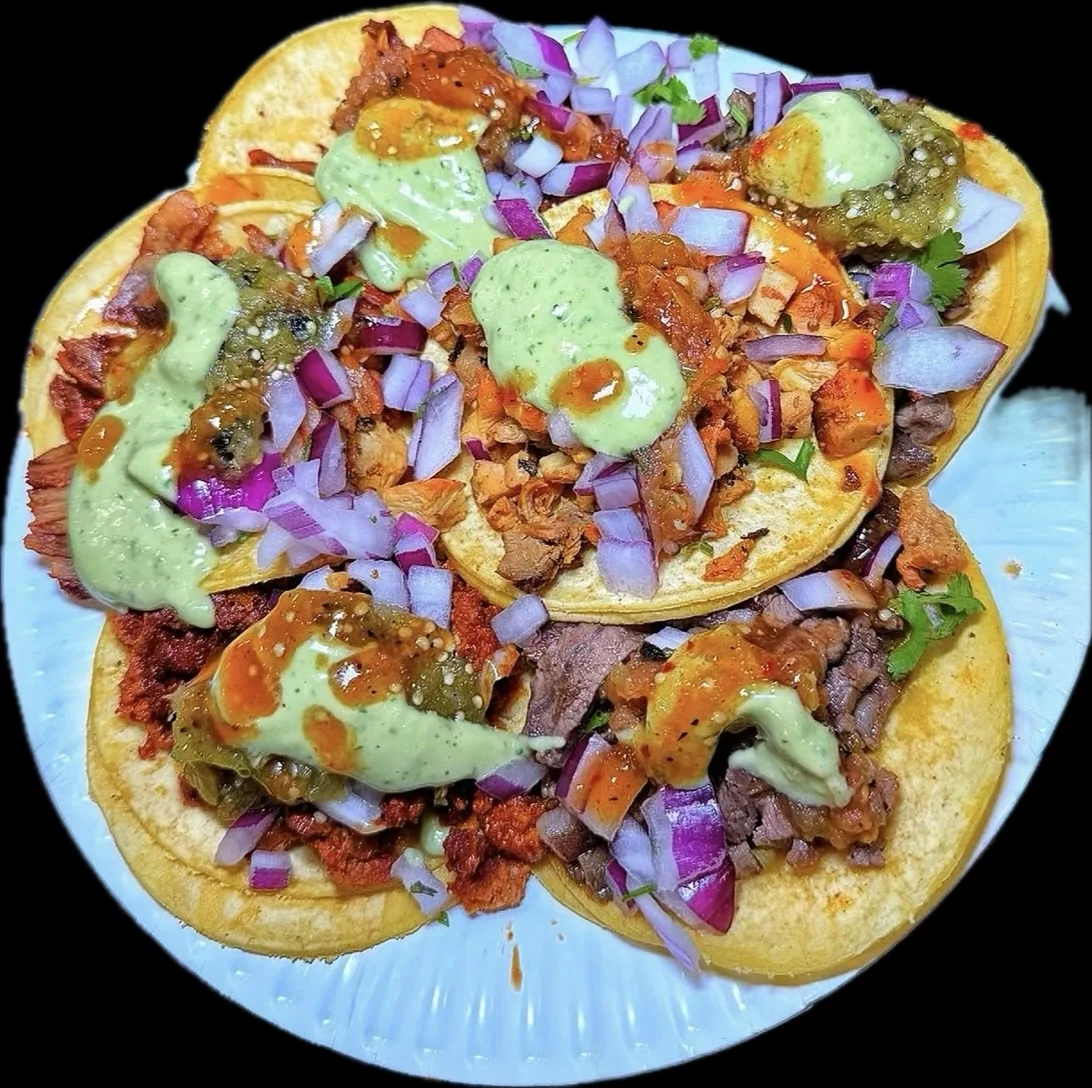 A colorful plate of tacos with onions, salsa, and crema