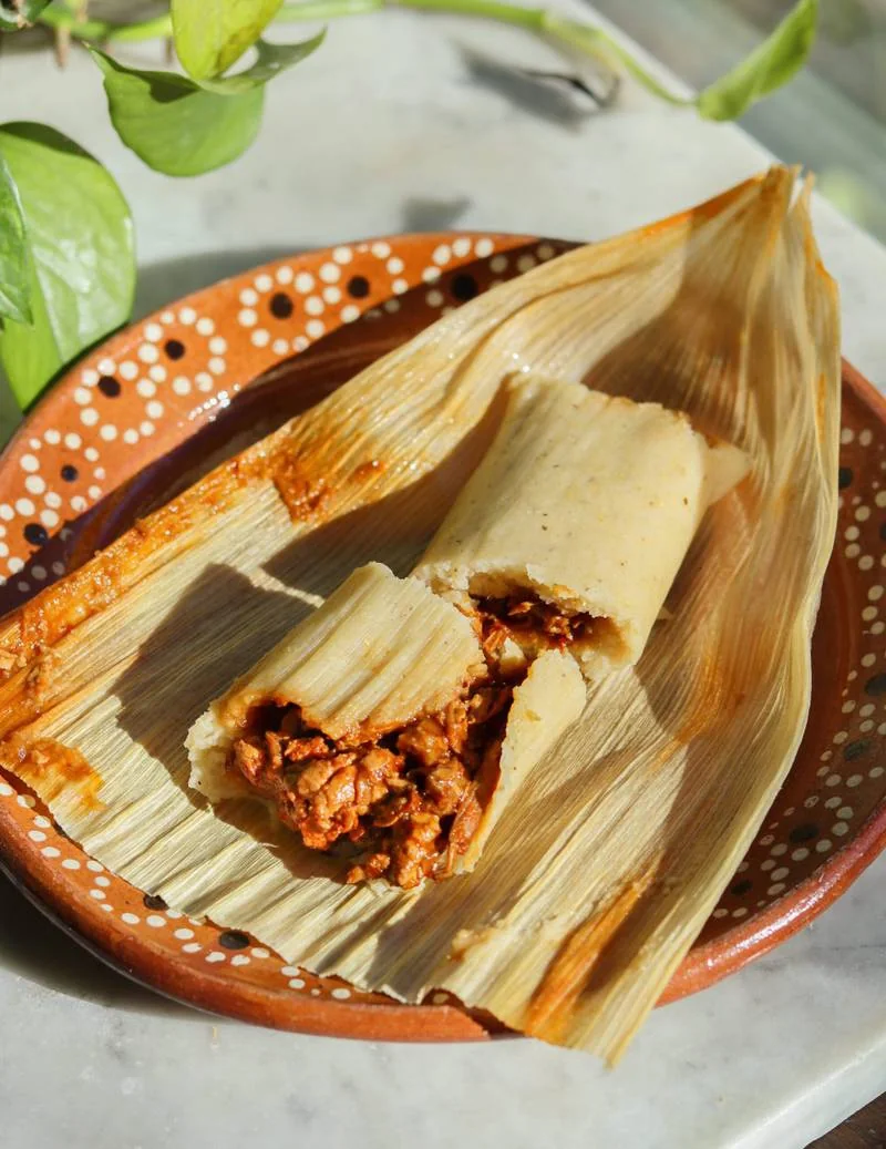 A house tamal opened on a traditional clay plate
